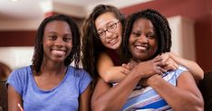 three women sitting on a couch hugging each other