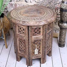 an ornate wooden table sitting on top of a white floor next to two vases