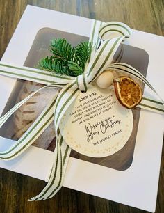 an orange slice tied with a green ribbon on top of a white gift box that says merry christmas