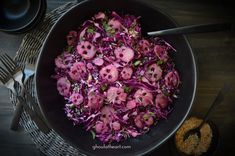 a bowl filled with red cabbage and skulls on top of a table next to silverware