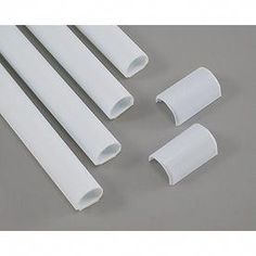 four white plastic tubes on a gray surface with one tube in the middle and three end pieces