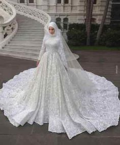 a woman in a white wedding gown standing on the steps outside an ornate building with stairs