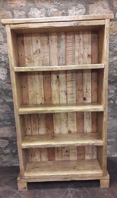 an old wooden bookcase is sitting in front of a stone wall with wood planks