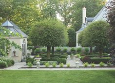 a garden with trees and bushes in front of a house