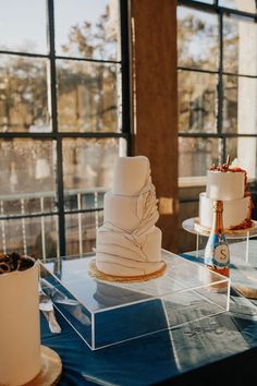 three tiered cake sitting on top of a table next to two large glass windows