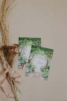 the wedding stationery is laid out next to some dried grass and flowers, along with two cards