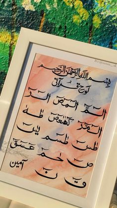 an arabic calligraphy is displayed in a white frame on a colorful wallpapered background