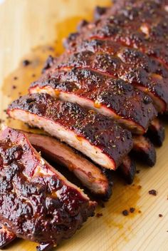 barbecue ribs covered in bbq sauce on a cutting board with seasoning sprinkled around them