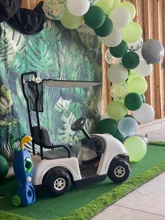 a golf cart is parked in front of a balloon arch with balloons on the wall