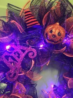 a purple and orange halloween wreath with a pumpkin on it