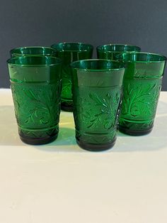 six green glass cups sitting on top of a table