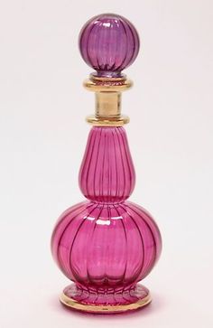 a pink glass perfume bottle sitting on top of a table