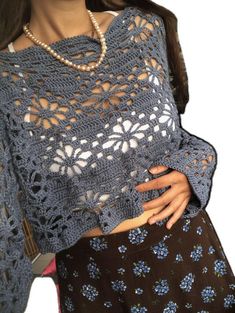 a woman wearing a blue crocheted shawl with flowers on the bottom and sides