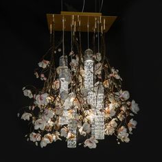 a chandelier with flowers hanging from it's sides and lights in the middle