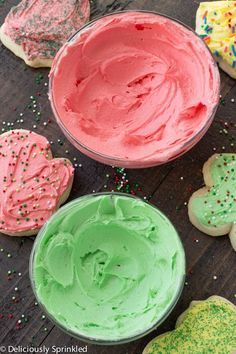 colorful frosted cookies and cupcakes with sprinkles on the table