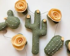 three felt cactus decorations with flowers on them