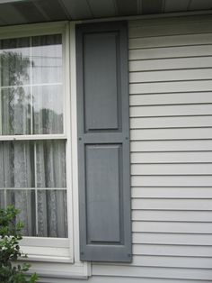 an open window on the side of a house with white siding and gray shutters