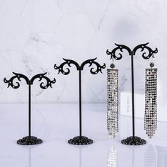 three pairs of earrings are on display in front of a white marble wall and floor