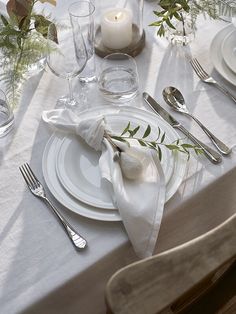 the table is set with white plates and silverware, napkins, and candles