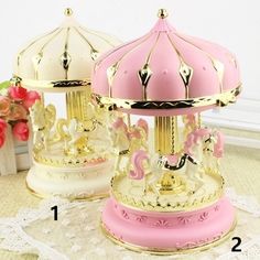 two pink and white carousels sitting next to each other on top of a table