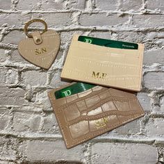 two personalized leather credit cards and a keychain hanging on a brick wall