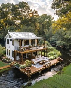 a house on the water with a deck in front of it and an outdoor seating area