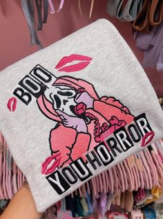 a person holding up a bag with the words bud your horror on it in front of a rack of clothes