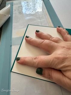 a woman's hand on top of a piece of paper next to some scissors