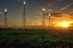 the sun is setting behind power lines in an open field with green grass and trees