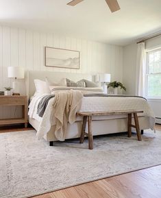 a bedroom with white walls and wood flooring has a large bed in the center