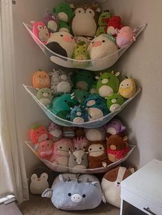 three tiered shelves filled with stuffed animals and other stuff toys in a corner next to a window