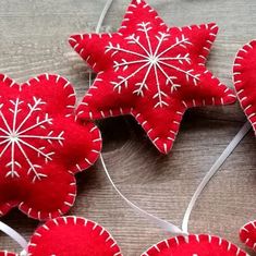 some red ornaments are hanging on a string and have white snowflakes attached to them