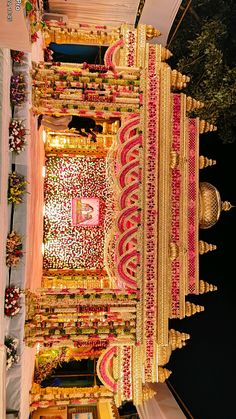 an elaborately decorated building with gold and pink decorations on the outside, in front of a tree