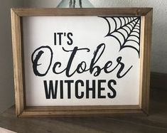 it's october witches sign in a wooden frame on a shelf next to a vase