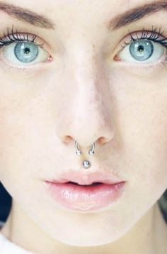 a woman with blue eyes and piercing on her nose