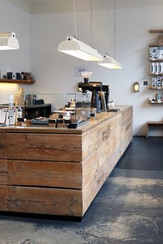 a large wooden counter in a kitchen with lights hanging from it's ceiling and various food items on the counter