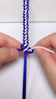 someone is tying a blue and white string together