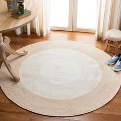 a white rug on the floor next to a wooden table and chair with blue shoes