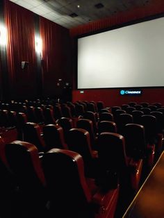 an empty auditorium with rows of seats and a projector screen in the middle of the room