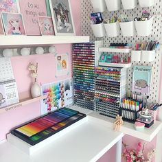 a desk with lots of different colored pens and markers on it, along with other office supplies