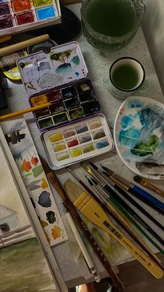 an artist's desk with watercolors, paints and brushes