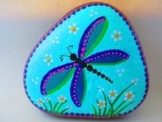 a painted rock with a dragonfly on it