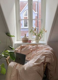 a bed sitting under a window next to a potted plant