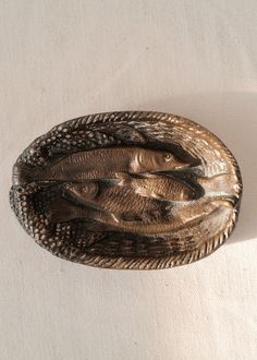 a metal brooch sitting on top of a white cloth covered table next to a wall