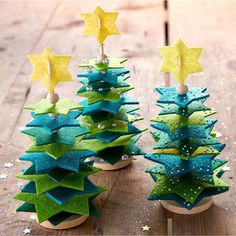 two small trees made out of felt sitting on top of a wooden table next to each other