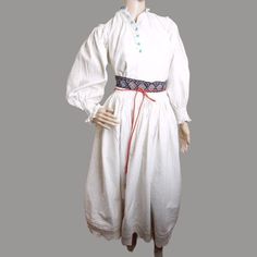 Antique Romanian folk outfit consisting of two pieces: Romanian blouse with white hand embroidery and Romanian peasant skirt . Traditional  costume from Transylvania for collectors or museums . The fabulous Romanian folk blouse with hand embroidered shoulders  has finest hand  embroidery on the sleeve, shoulders and cuffs hand made of beige cotton thread. The neck has blue stitches. The shirt is decorated with  the old blue glass buttons. The cuffs end with laces. Fits S-M measures. Although I added more cloth under the arm to make it wider and more comfortable to wear, the shirt still has a small collar and therefore only fits S-M measures. It has the following dimensions: shoulders: 34 cm (13.38 inches) neck: 33 cm or 13 inches sleeve length: 52 cm or 20.47 inches chest circumference: 14 Traditional Embroidered Peasant Dress, Traditional White Costume Dress, Fitted Peasant Dress For Daywear, Peasant Style Cotton Costume Dress, White Cotton Peasant Prairie Dress, White Peasant Dress For Daywear, Traditional Cotton Costume Dress, Spring Peasant Prairie Dress, Folk Outfit