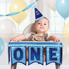 a baby sitting in a high chair with balloons and streamers around him that say one