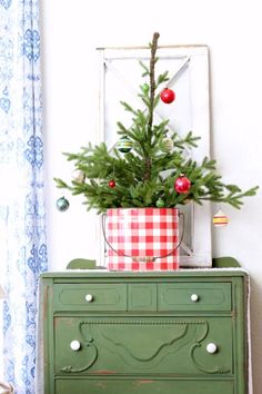 a small christmas tree sitting on top of a green dresser