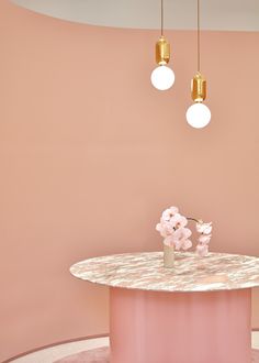 a pink table with flowers on it and two lights hanging from the ceiling