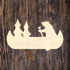 a wooden cutout of a bear and cub in a canoe with trees on the side